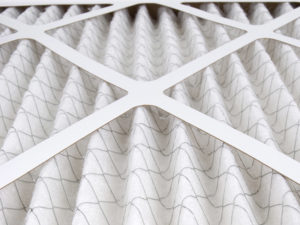 Close-up of a pleated air filter with a white frame and crisscross support structure.