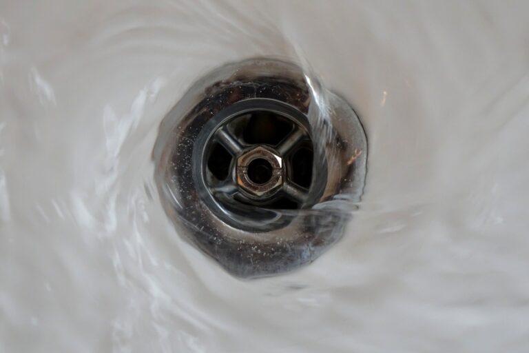 Close-up view of water swirling around a metal sink drain.