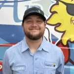Meet Our Team: A man wearing a blue work shirt and black cap stands in front of a colorful vehicle with a sun graphic. The name "Jonathan" is visible on his shirt.